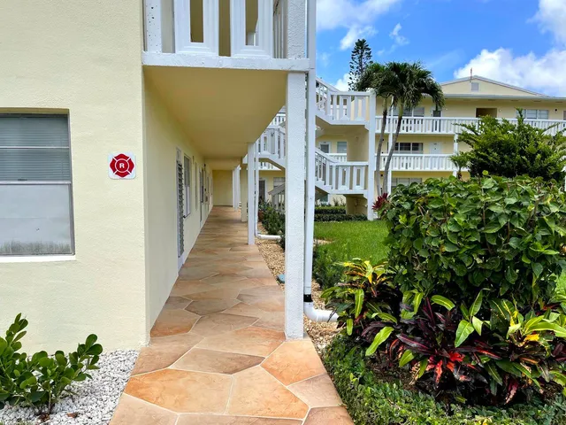 a front view of a building with a garden and trees