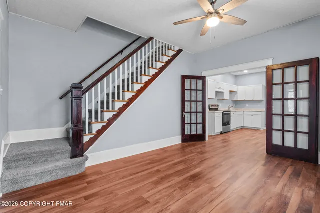 a view of an empty room with kitchen and window
