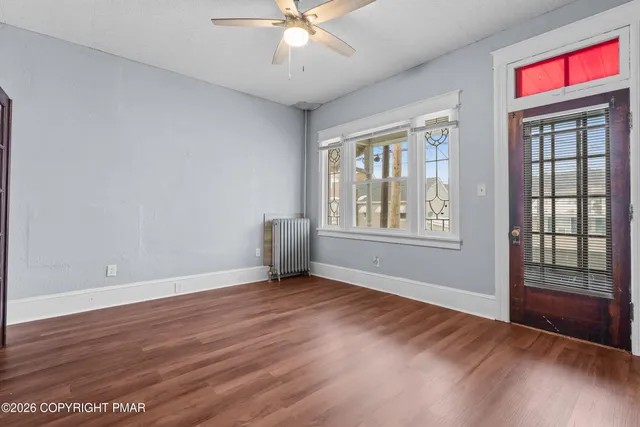 a view of an empty room with a window and wooden floor