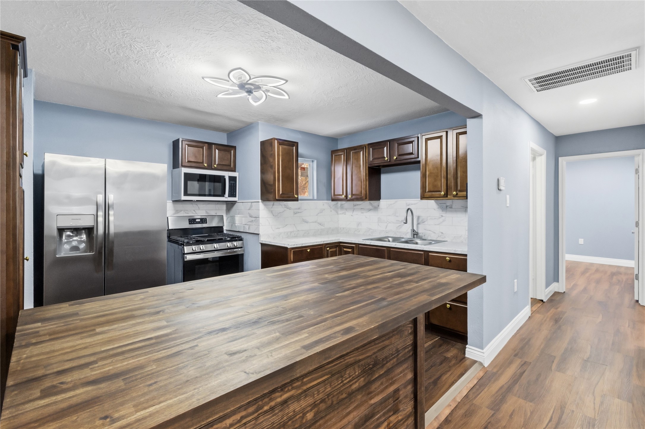 901 South 7th Street Baytown, TX 77520 - Photo 16 of 36 a kitchen with stainless steel appliances wooden floor and refrigerator