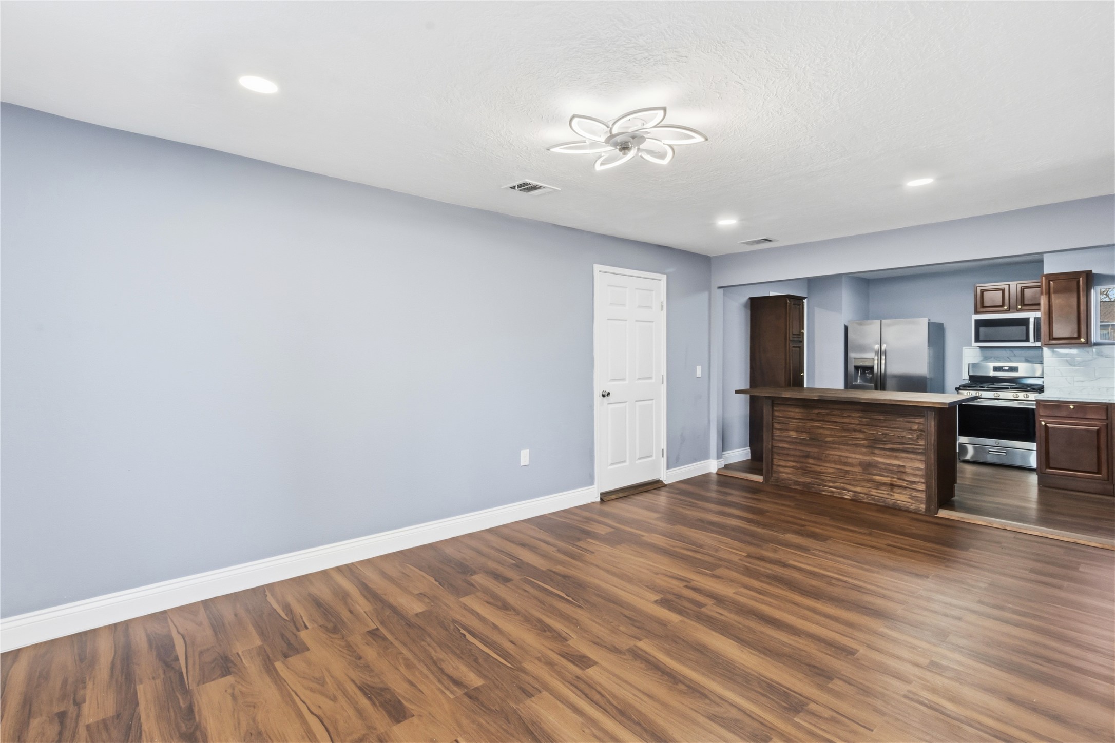 901 South 7th Street Baytown, TX 77520 - Photo 9 of 36 a view of an empty room with wooden floor and a kitchen