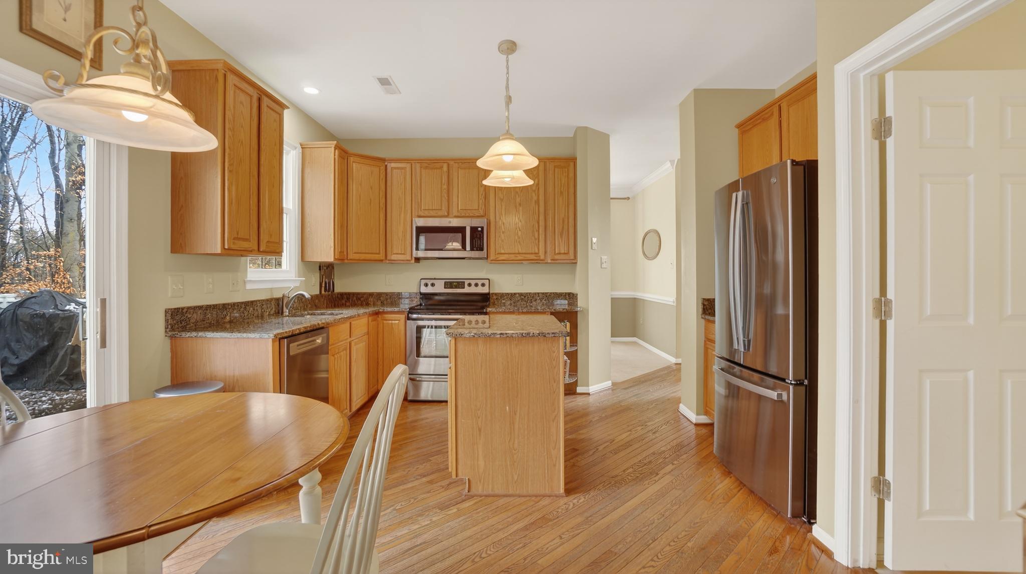2806 Erna Court Crofton, MD 21054 - Photo 16 of 60 a kitchen with kitchen island granite countertop wooden floor and stainless steel appliances