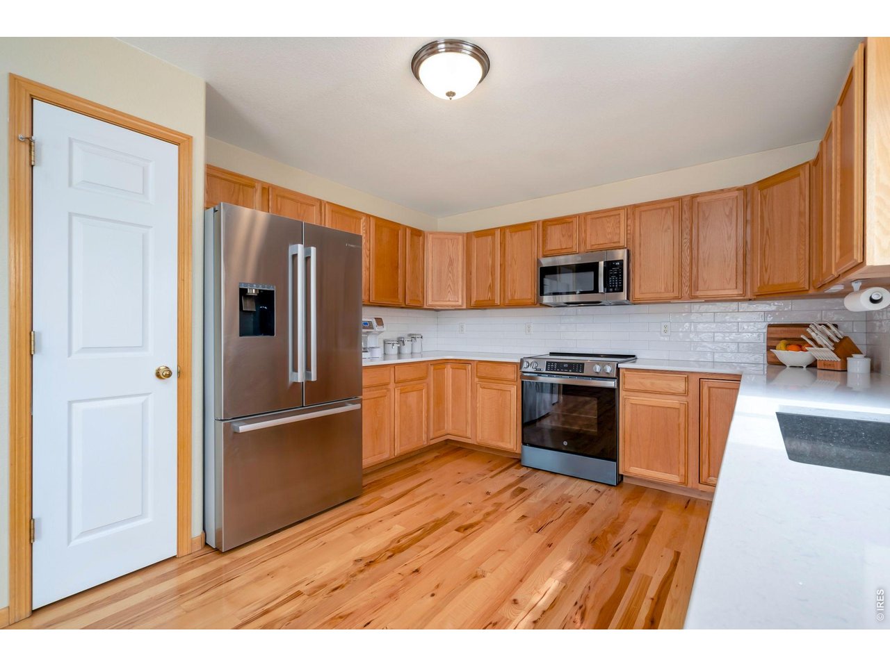 3779 Mount Meeker Street Wellington, CO 80549 - Photo 5 of 30 a kitchen with granite countertop wooden floors and stainless steel appliances