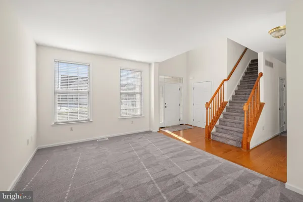 a view of an empty room with wooden floor and stairs