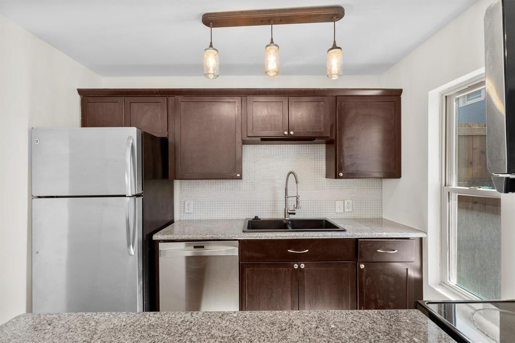 Kitchen with dark brown cabinetry, tasteful backsplash, appliances with stainless steel finishes, and a sink