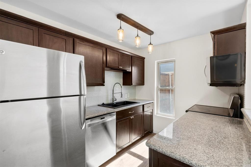 4039 Cole Avenue, Unit 105 Dallas, TX 75204 - Photo 13 of 39 Kitchen with appliances with stainless steel finishes, a sink, backsplash, and dark brown cabinets