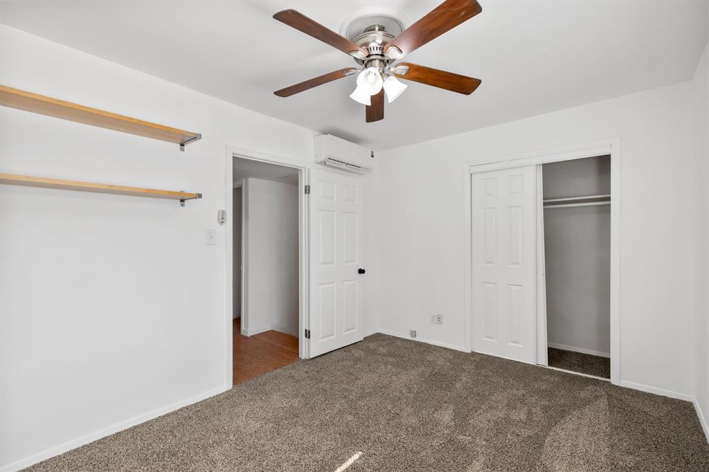 4039 Cole Avenue, Unit 105 Dallas, TX 75204 - Photo 20 of 39 Unfurnished bedroom featuring carpet floors, a ceiling fan, baseboards, a closet, and a wall mounted air conditioner