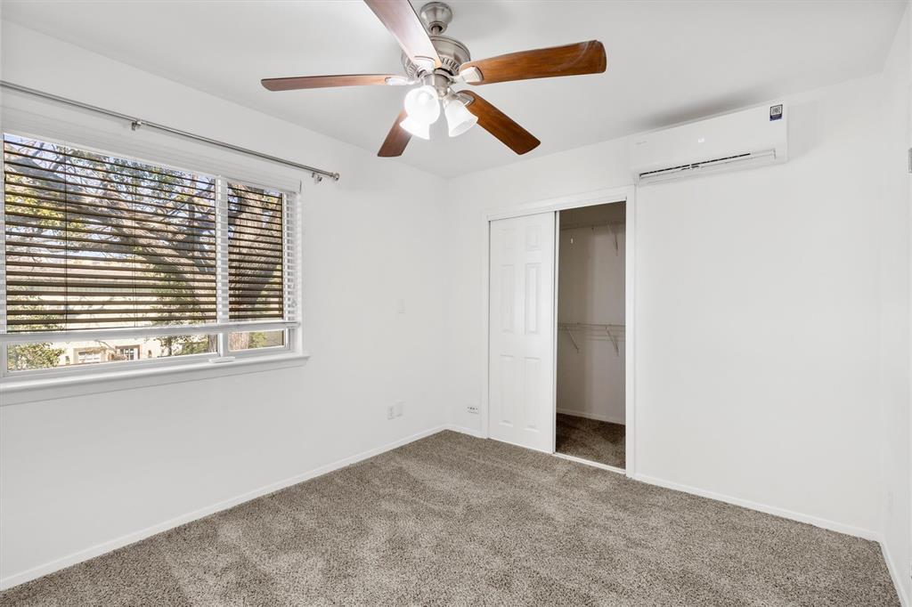 4039 Cole Avenue, Unit 105 Dallas, TX 75204 - Photo 23 of 39 Unfurnished bedroom with an AC wall unit, a closet, carpet, and baseboards