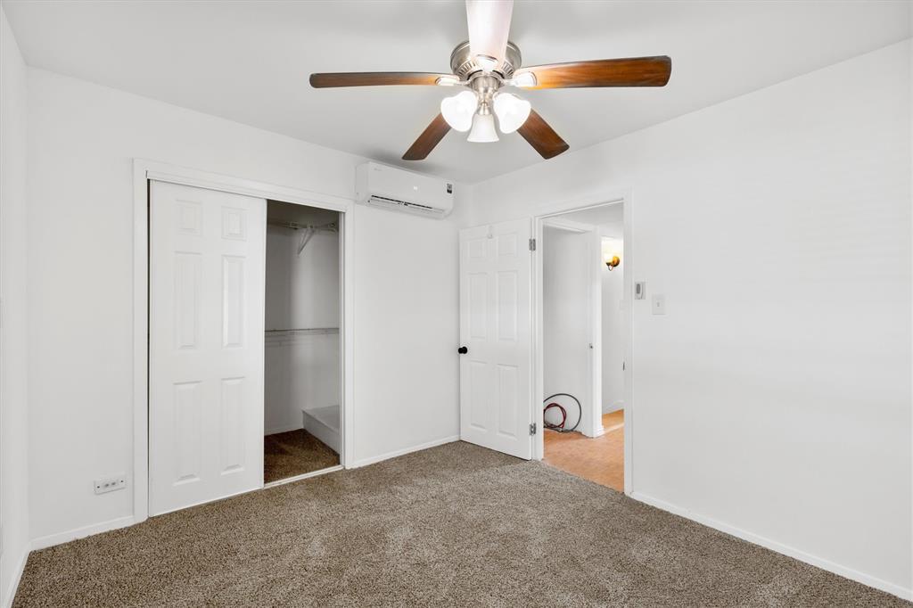 4039 Cole Avenue, Unit 105 Dallas, TX 75204 - Photo 24 of 39 Unfurnished bedroom with baseboards, a ceiling fan, a wall unit AC, carpet, and a closet