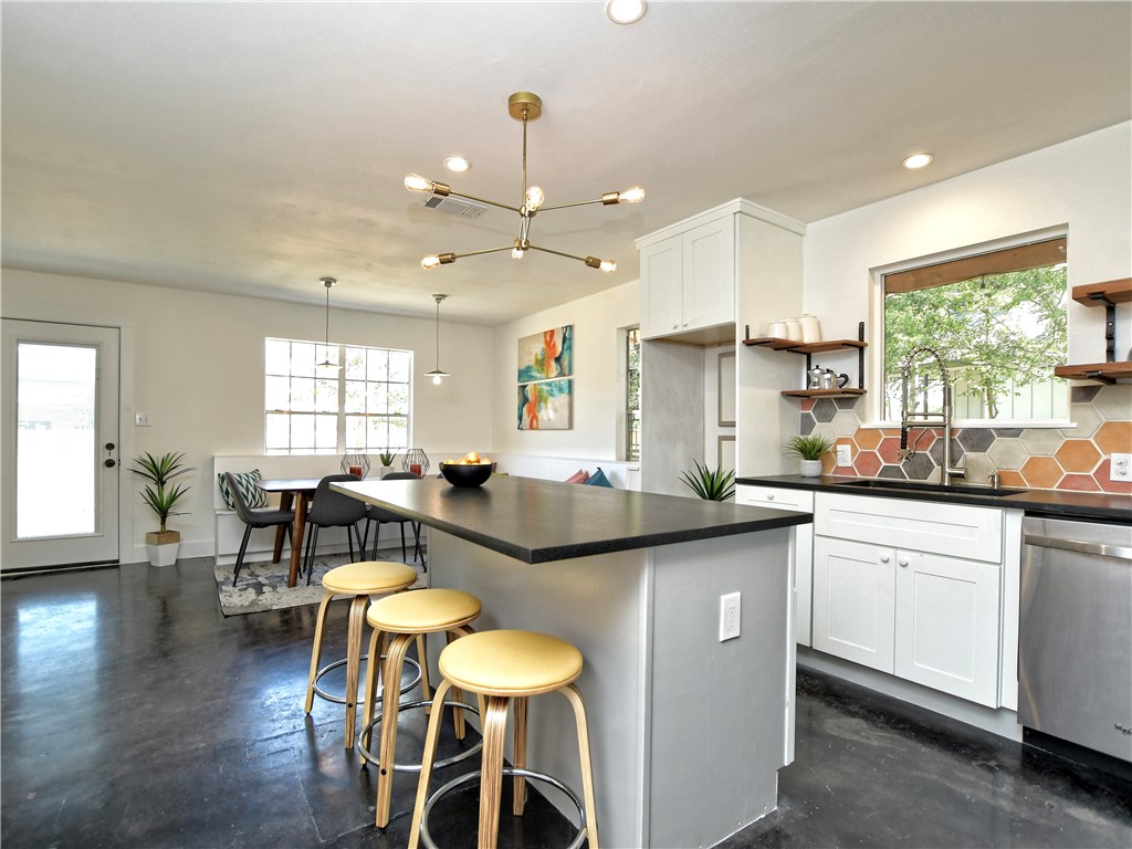 a kitchen with stainless steel appliances granite countertop a stove a sink a dining table and chairs with wooden floor