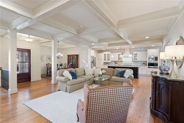 a living room with furniture a wooden floor and kitchen view