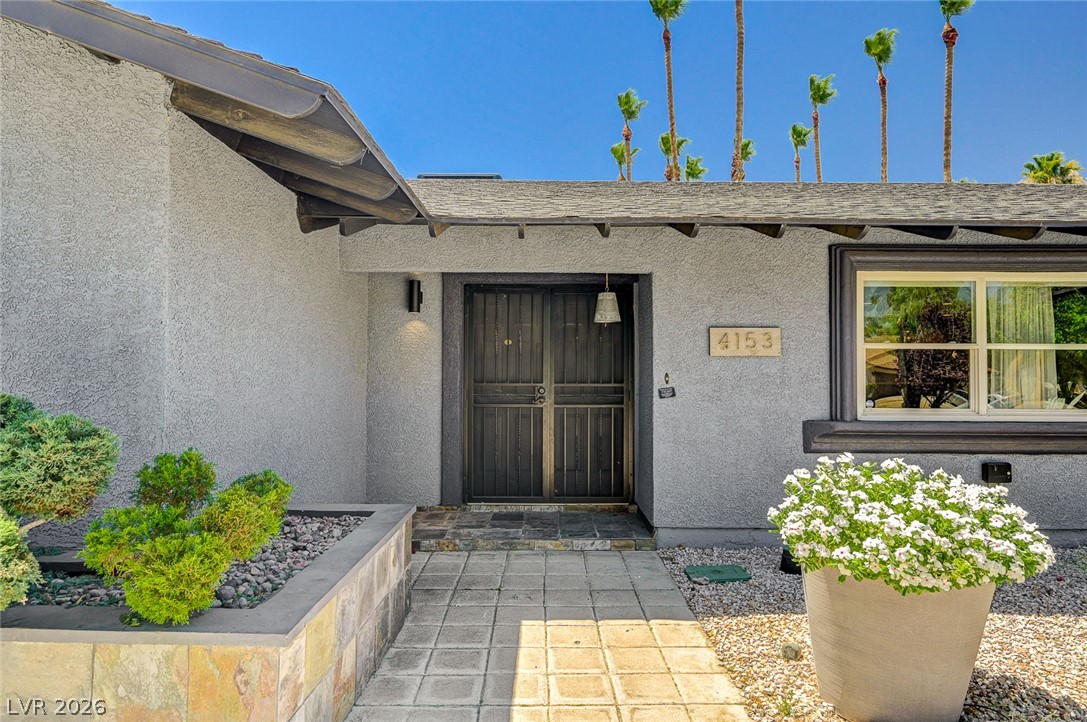 4153 Woodcrest Road Las Vegas, NV 89121 - Photo 7 of 58 A welcoming stone walkway leads to the secure double entry doors, framed by lush desert landscaping.