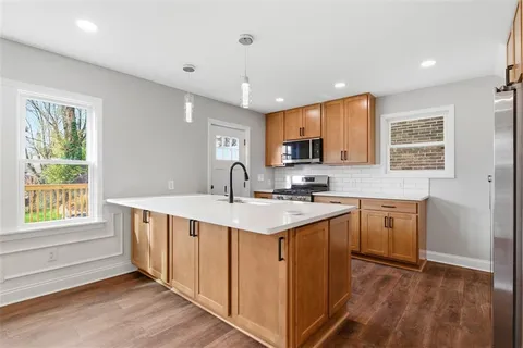 a kitchen with stainless steel appliances granite countertop a sink a stove a refrigerator cabinets and a window