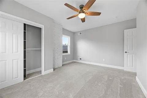 an empty room with closet and a ceiling fan