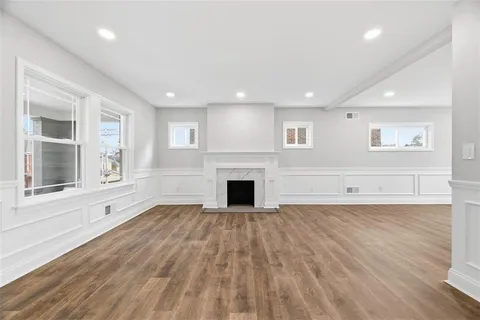 an empty room with wooden floor fireplace and windows