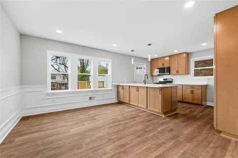 a large white kitchen with kitchen island granite countertop a stove top oven and a sink with granite countertops