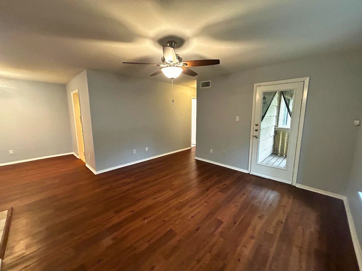 This living area features rich hardwood flooring and a ceiling fan with integrated lighting