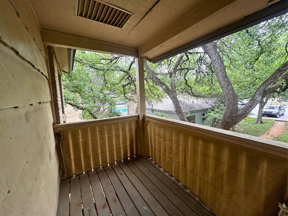 8210 Bent Tree Road, Unit 247 Austin, TX 78759 - Photo 12 of 21 The property features a balcony with wooden floorboards and a light-colored railing, offering a view of mature trees