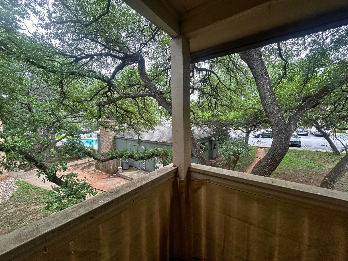 8210 Bent Tree Road, Unit 247 Austin, TX 78759 - Photo 13 of 21 View from the property overlooking mature trees, a swimming pool, and a nearby building with a shingled roof