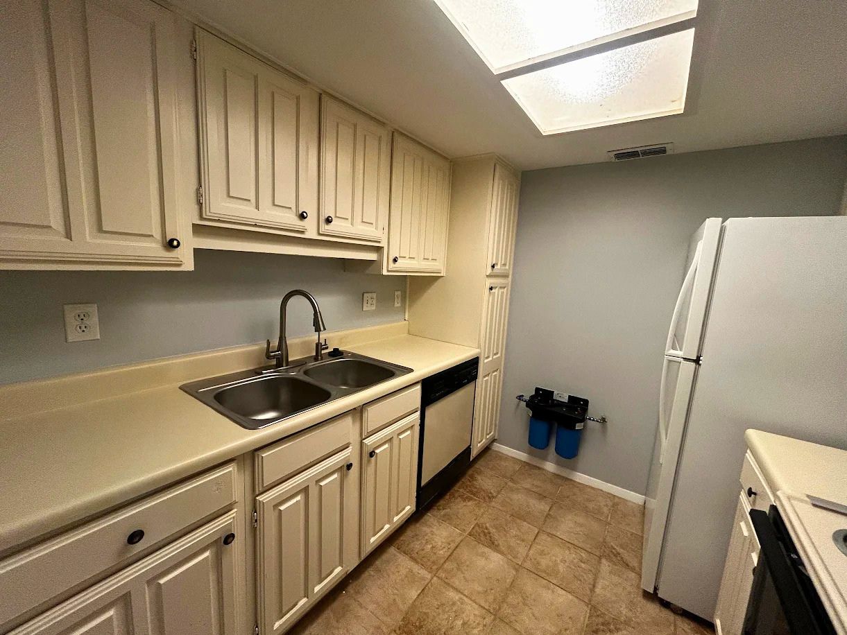 8210 Bent Tree Road, Unit 247 Austin, TX 78759 - Photo 3 of 21 The kitchen features ample cabinetry, a double basin stainless steel sink with a gooseneck faucet, light-colored countertops, and a full-size refrigerator