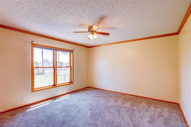 an empty room with windows and a chandelier fan
