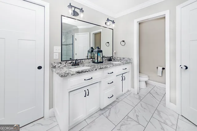 a bathroom with a granite countertop sink mirror and a toilet