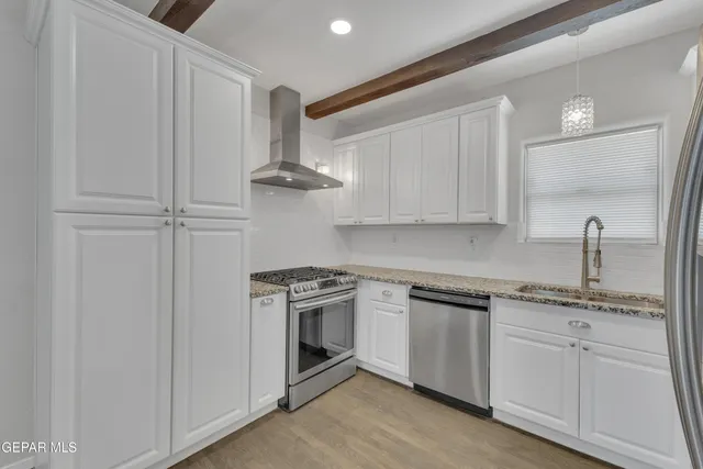 a kitchen with stainless steel appliances granite countertop white cabinets and a sink