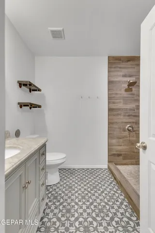 a bathroom with a granite countertop sink a toilet and a shower