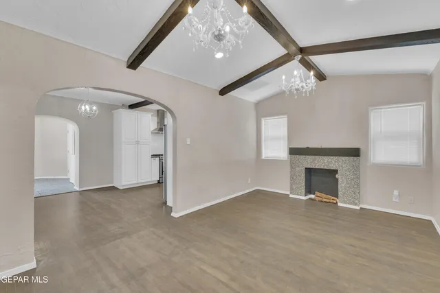 a view of an empty room with a fireplace and a chandelier fan