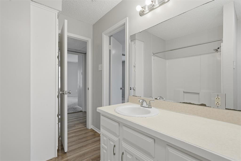 2332 Melissa Drive Waco, TX 76708 - Photo 11 of 15 Full bath featuring a textured ceiling, vanity, light wood-style floors, and a shower