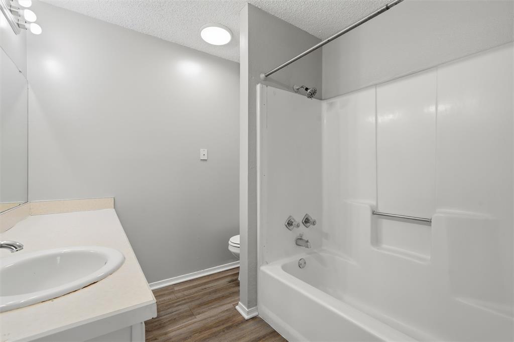 2332 Melissa Drive Waco, TX 76708 - Photo 14 of 15 Full bath featuring vanity, a textured ceiling, bathing tub / shower combination, and dark wood finished floors