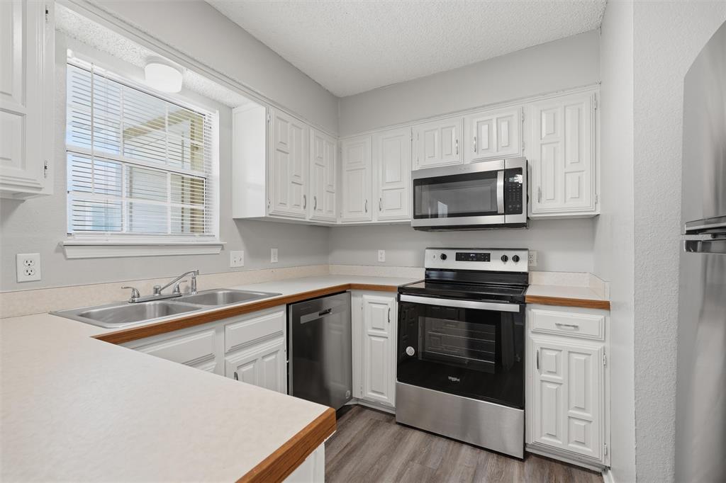 2332 Melissa Drive Waco, TX 76708 - Photo 7 of 15 Kitchen featuring light countertops, stainless steel appliances, white cabinetry, light wood finished floors, and a textured ceiling