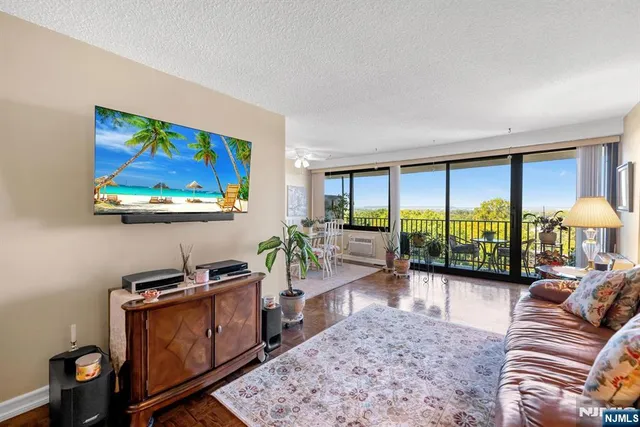 a living room with furniture a rug floor to ceiling window and a flat screen tv