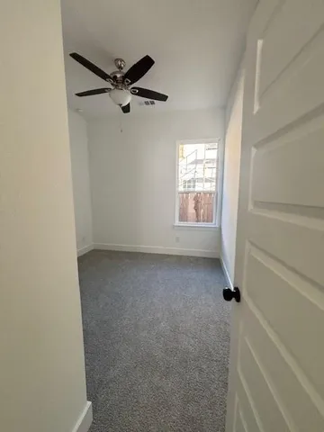 a view of a hallway with wooden floor and a bathroom