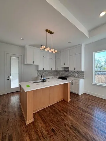 a kitchen with a sink cabinets wooden floor and a window