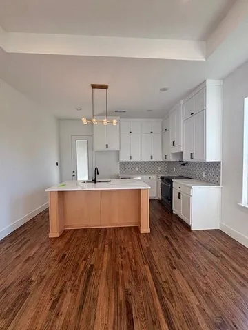 a kitchen with wooden floor sink and cabinets