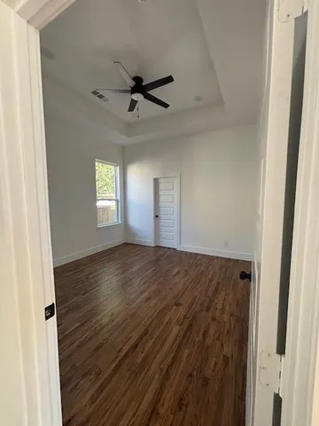 a view of empty room with wooden floor and window