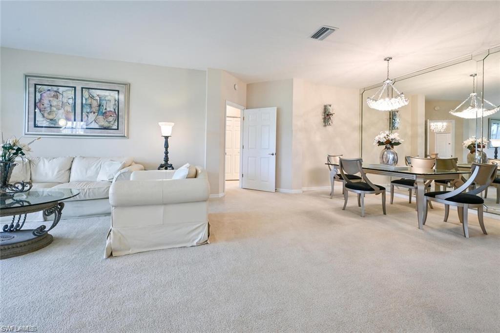 6065 Pinnacle Lane, Unit 1001 Naples, FL 34110 - Photo 11 of 26 a living room with furniture and a chandelier