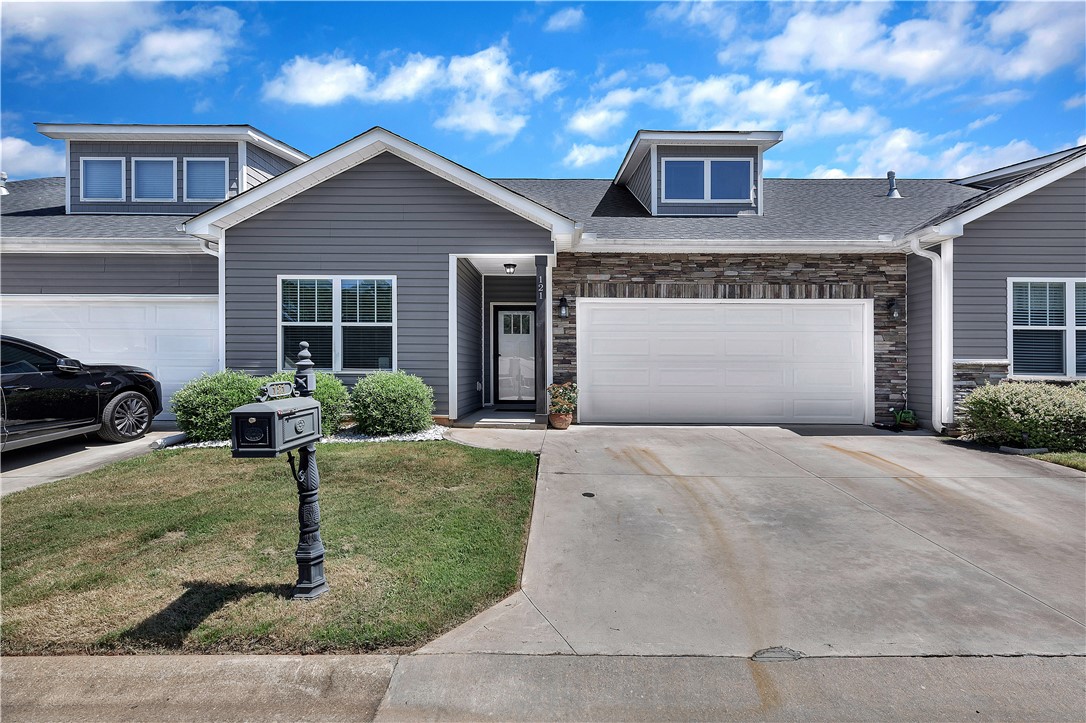 A welcoming front exterior features a combination of stone and siding with neatly maintained landscaping.
