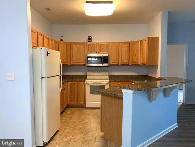 a kitchen with granite countertop a refrigerator and a sink