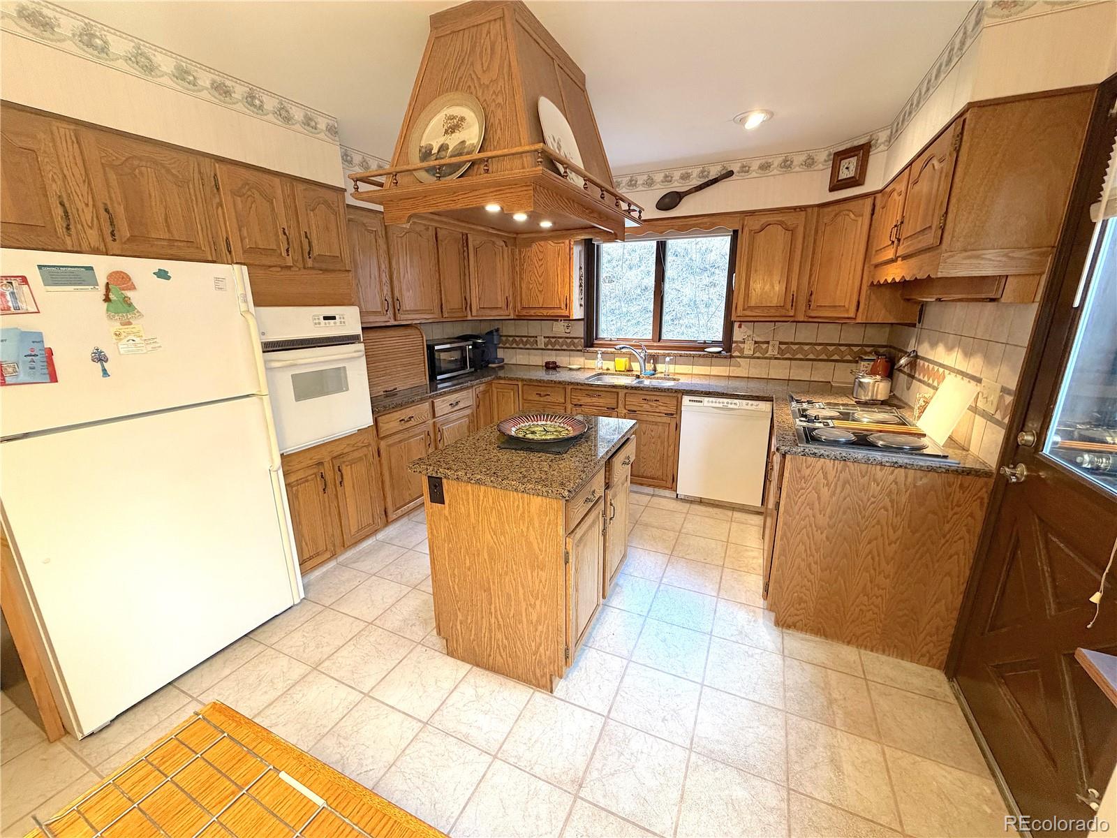 2508 Witter Gulch Road Evergreen, CO 80439 - Photo 30 of 47 a kitchen with a sink a refrigerator and cabinets