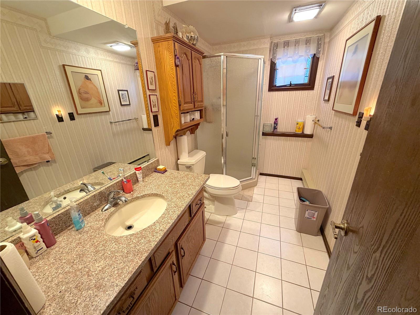 2508 Witter Gulch Road Evergreen, CO 80439 - Photo 31 of 47 a bathroom with a granite countertop sink a mirror and shower