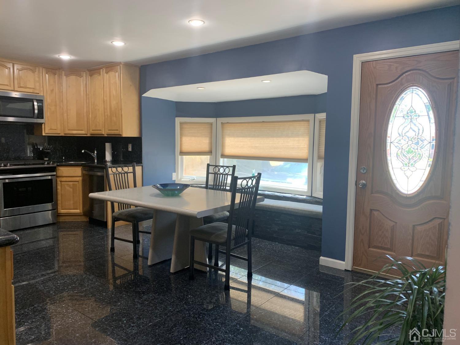 19 Columbia Road Old Bridge, NJ 08859 - Photo 7 of 24 a kitchen with stainless steel appliances granite countertop a stove a sink a microwave a dining table and chairs with wooden floor