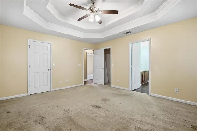 an empty room with chandelier fan and windows