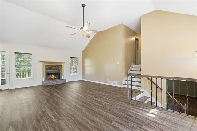 an empty room with wooden floor fireplace and windows
