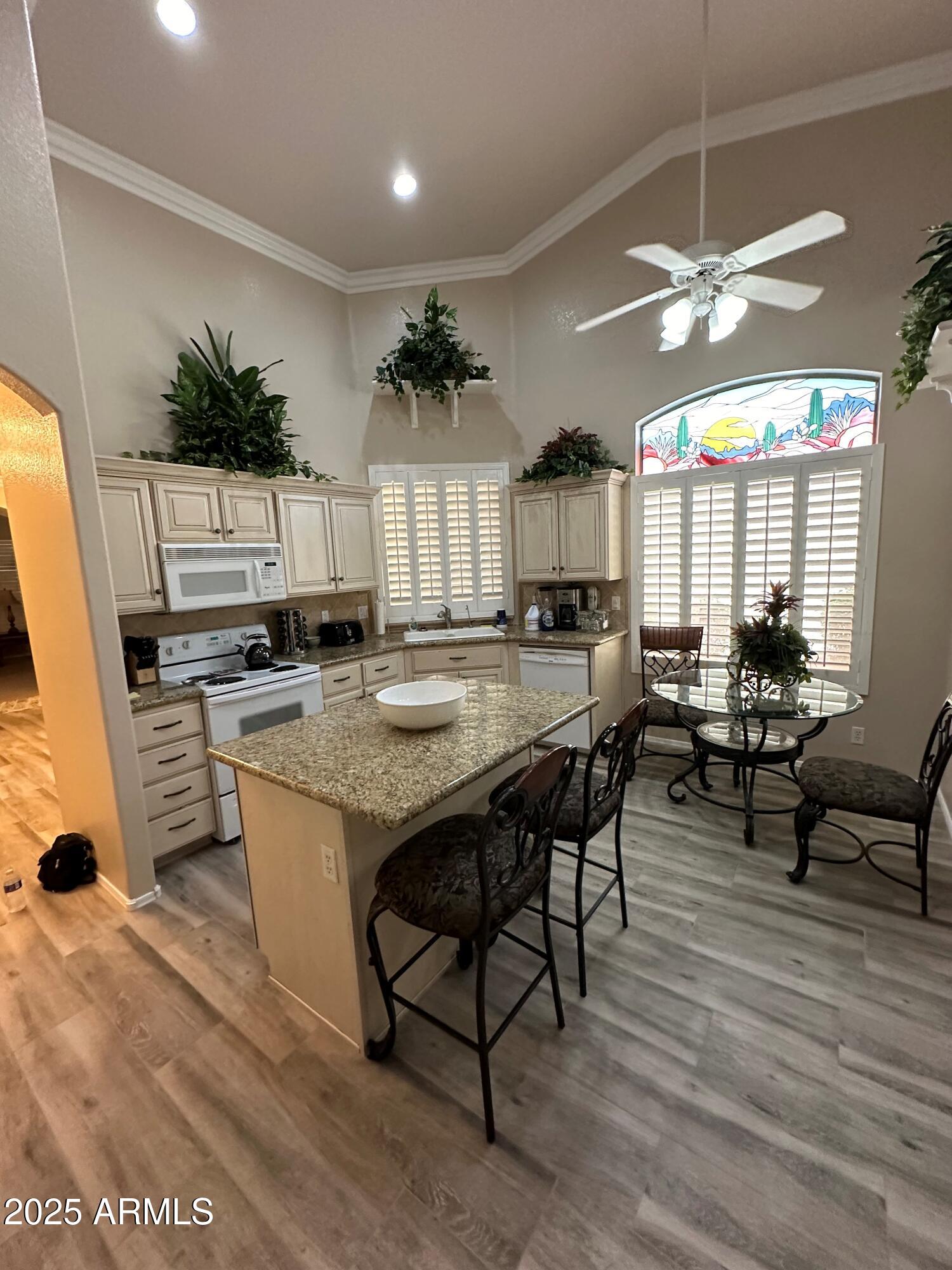 9757 East Tranquility Way Sun Lakes, AZ 85248 - Photo 4 of 10 a kitchen with stainless steel appliances kitchen island granite countertop a table chairs and a refrigerator