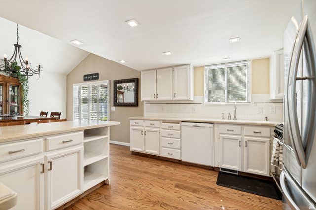 9832 Falconhurst Drive Sandy, UT 84092 - Photo 9 of 29 Bright kitchen featuring white cabinetry, light-toned countertops, and wood-finish flooring