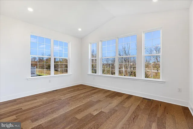 a view of an empty room with a window and wooden floor