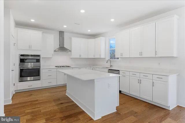 a kitchen with stainless steel appliances granite countertop a stove a sink and white cabinets