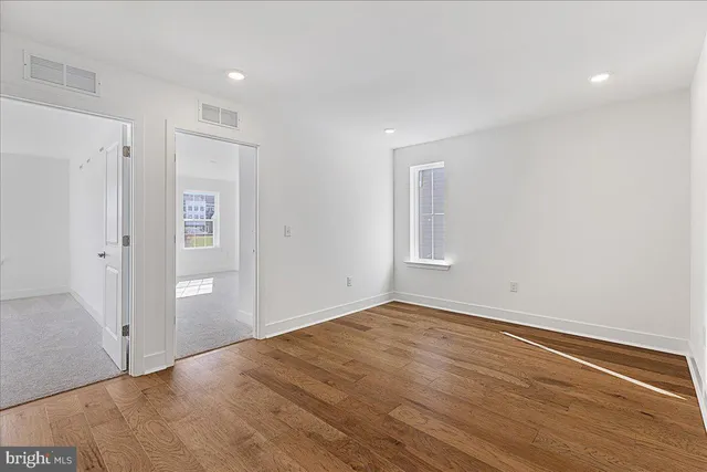 a view of an empty room with wooden floor and closet